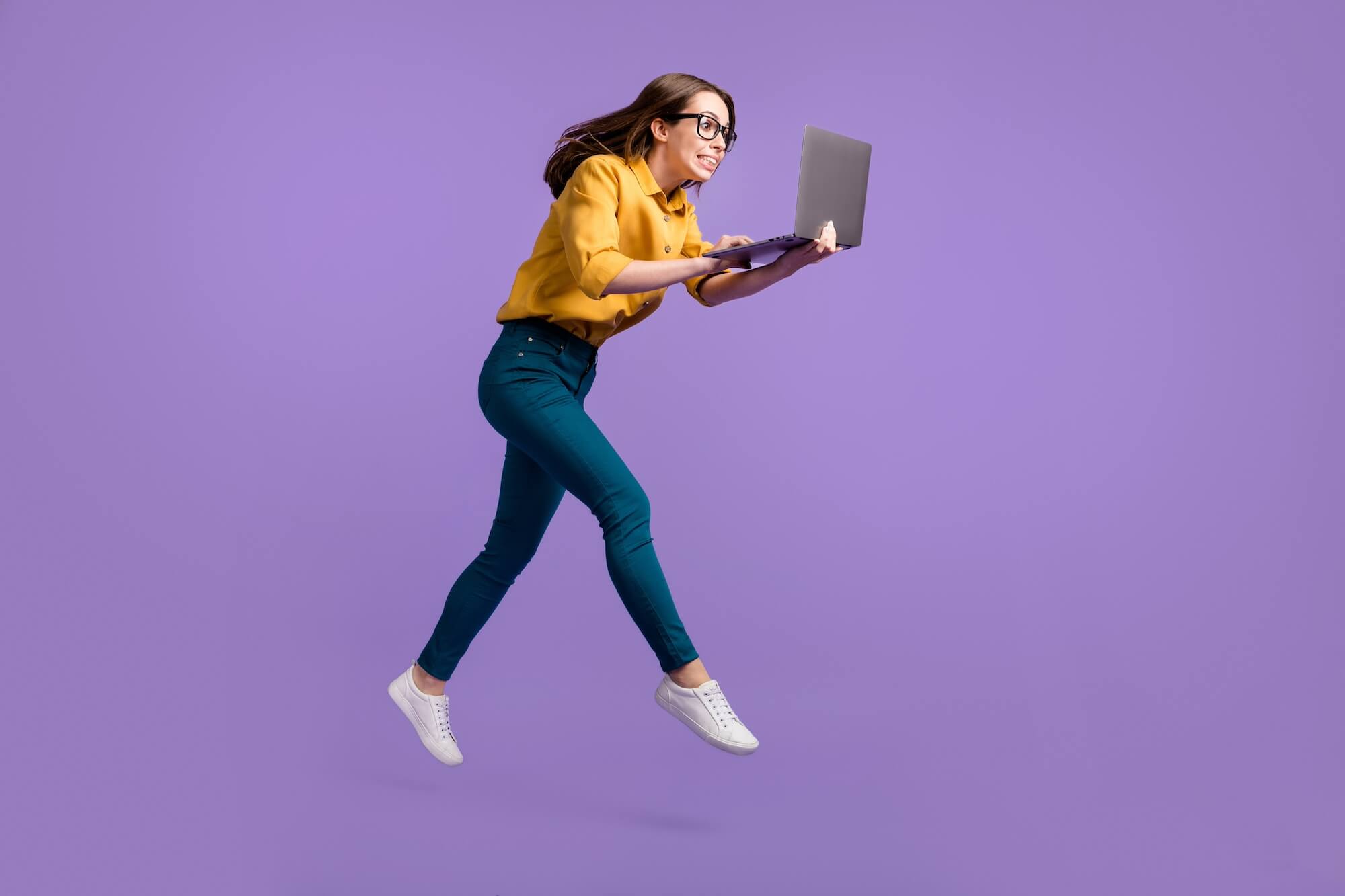 女性がのーとPCを開けて持ち画面を見つめて飛び上がっている